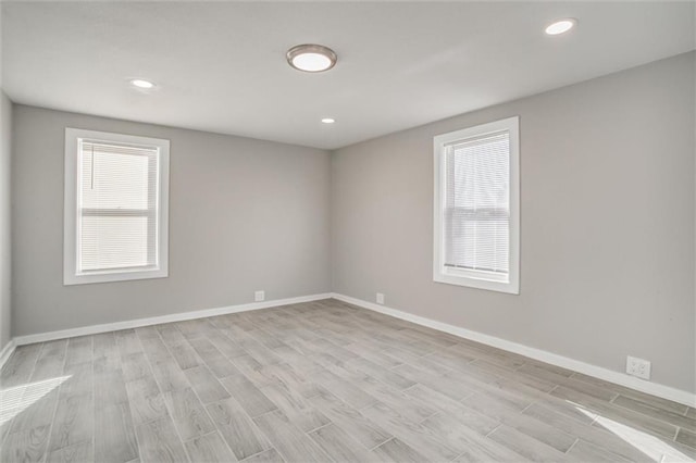 empty room with recessed lighting, light wood-type flooring, and baseboards