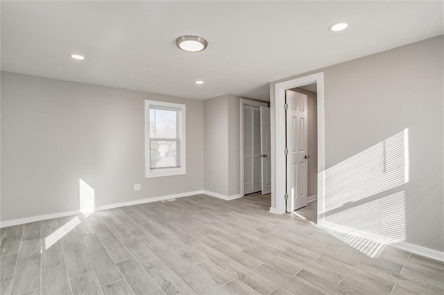 spare room featuring recessed lighting, baseboards, and light wood-style floors