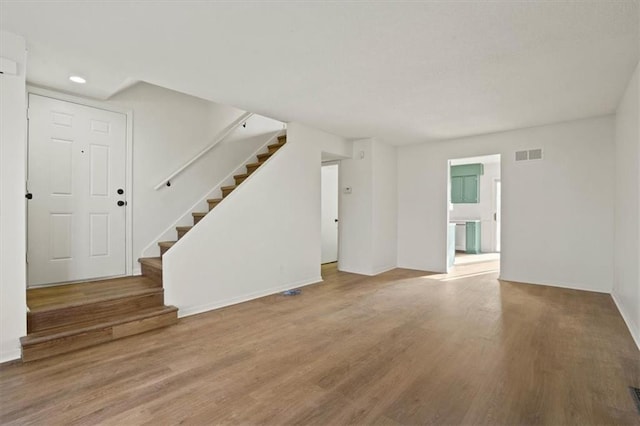 unfurnished living room with stairs, wood finished floors, and visible vents