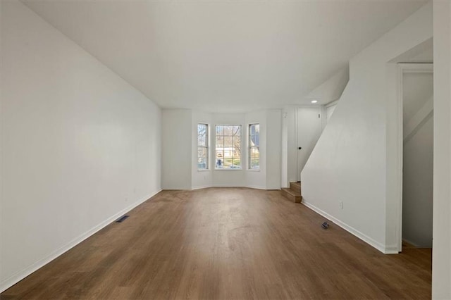 unfurnished living room featuring stairs, wood finished floors, visible vents, and baseboards