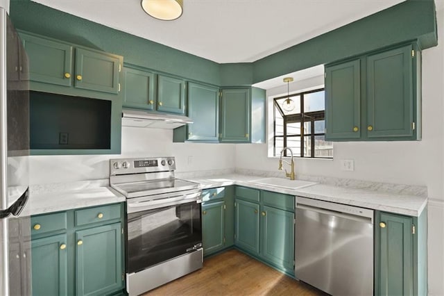 kitchen featuring dark wood-type flooring, under cabinet range hood, light countertops, appliances with stainless steel finishes, and a sink