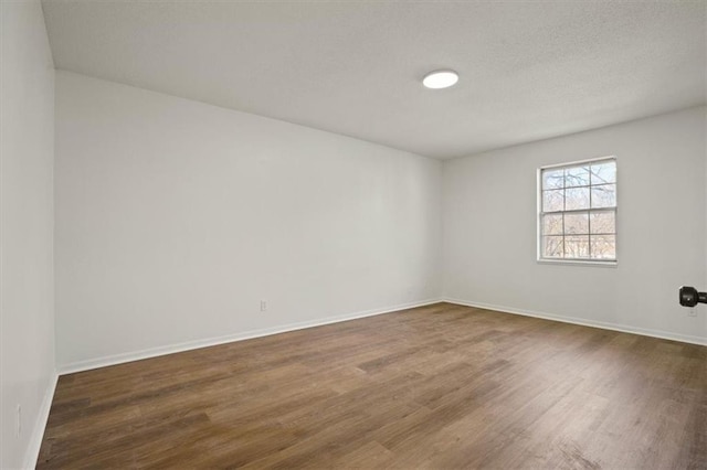 spare room with a textured ceiling, baseboards, and wood finished floors