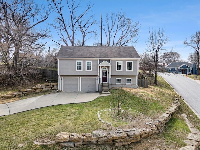 split foyer home featuring a front lawn, an attached garage, driveway, and fence