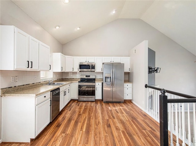 kitchen with white cabinets, stainless steel appliances, light wood-type flooring, and a sink