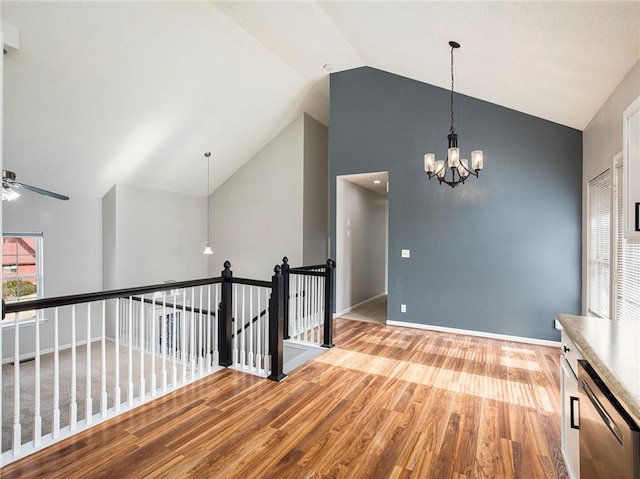 interior space featuring wood finished floors, baseboards, high vaulted ceiling, an upstairs landing, and a chandelier