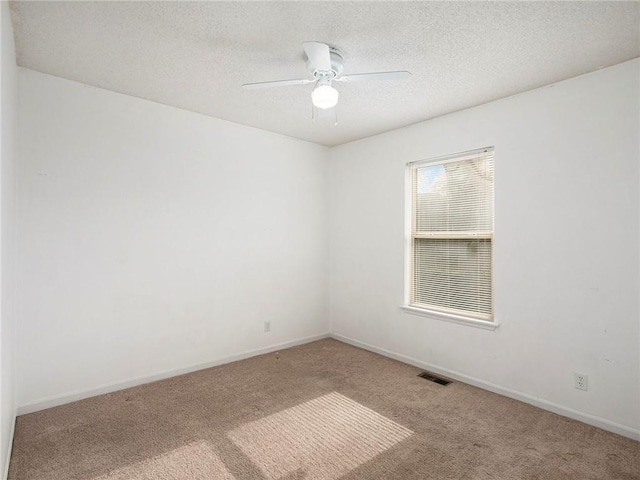 carpeted empty room featuring baseboards, visible vents, a textured ceiling, and ceiling fan