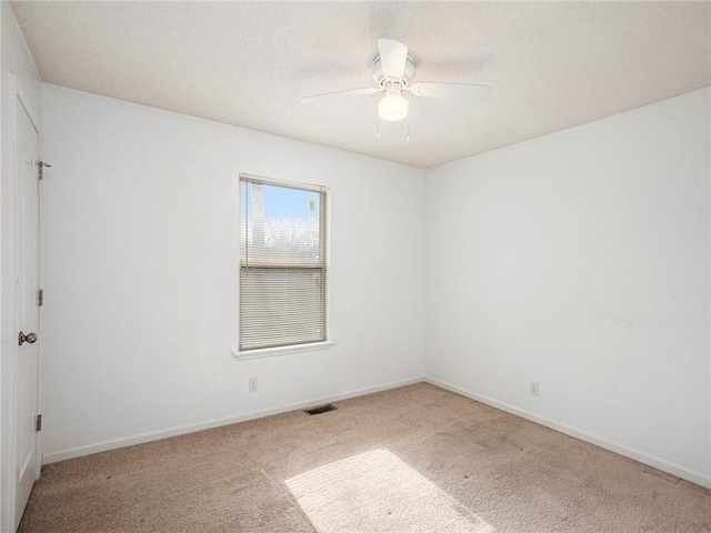 spare room featuring visible vents, a textured ceiling, carpet, baseboards, and ceiling fan