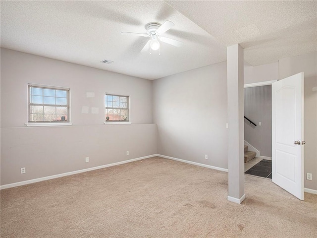 spare room with stairway, visible vents, ceiling fan, a textured ceiling, and light carpet