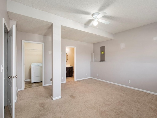 unfurnished bedroom featuring baseboards, washer / dryer, electric panel, a textured ceiling, and light colored carpet