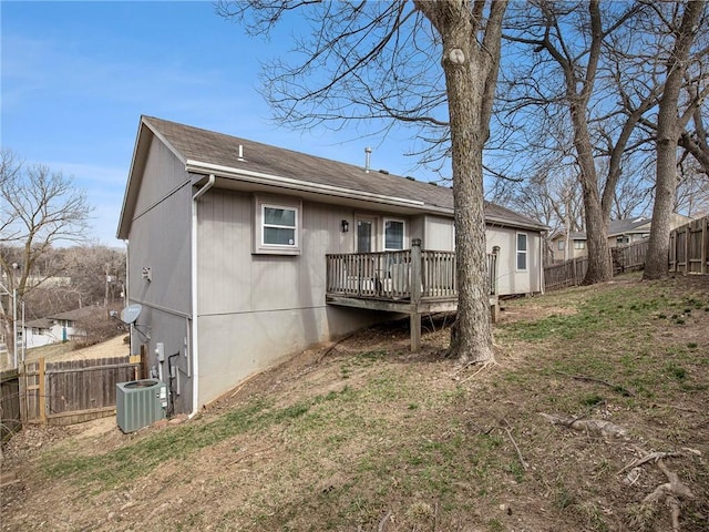 rear view of house featuring a lawn, a deck, a fenced backyard, a shingled roof, and central AC unit