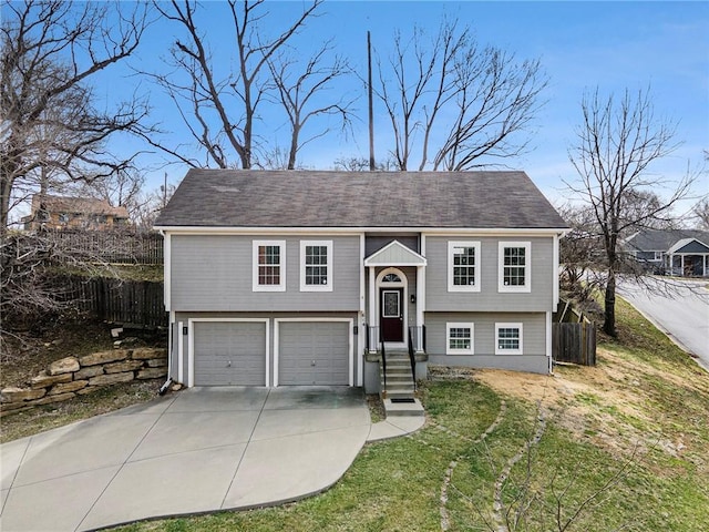 bi-level home featuring concrete driveway, an attached garage, and fence