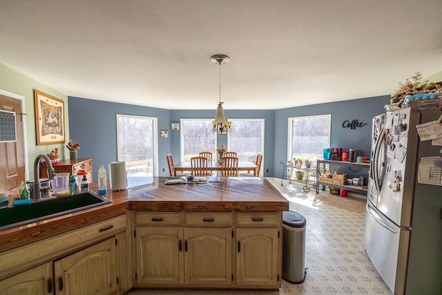 kitchen with a notable chandelier, a healthy amount of sunlight, freestanding refrigerator, and a sink