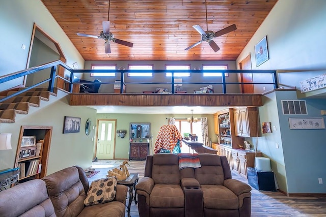 living room featuring wood finished floors, visible vents, a high ceiling, wooden ceiling, and ceiling fan with notable chandelier