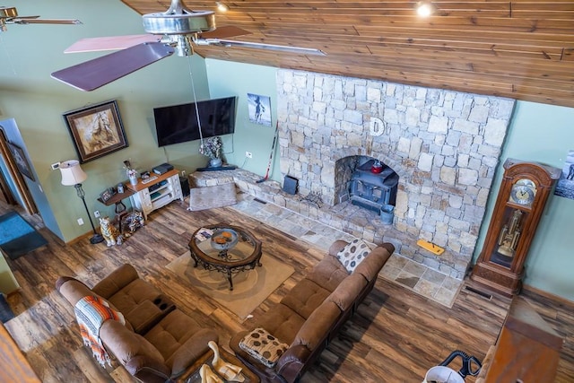 living area with a wood stove, wood finished floors, a ceiling fan, and vaulted ceiling