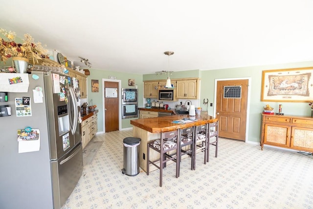 kitchen with dark countertops, a peninsula, a kitchen breakfast bar, stainless steel appliances, and a sink