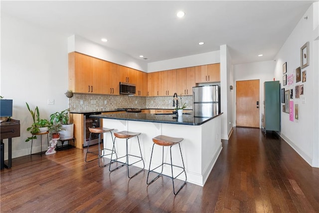 kitchen with beverage cooler, backsplash, appliances with stainless steel finishes, and a kitchen breakfast bar