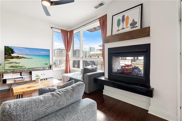 living room with visible vents, baseboards, a ceiling fan, and hardwood / wood-style flooring