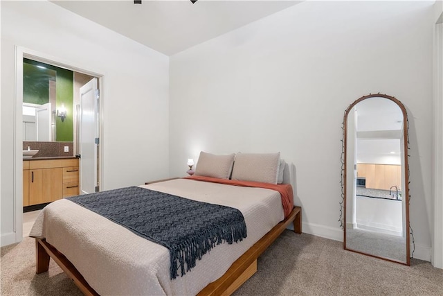 bedroom featuring baseboards, light carpet, and ensuite bathroom