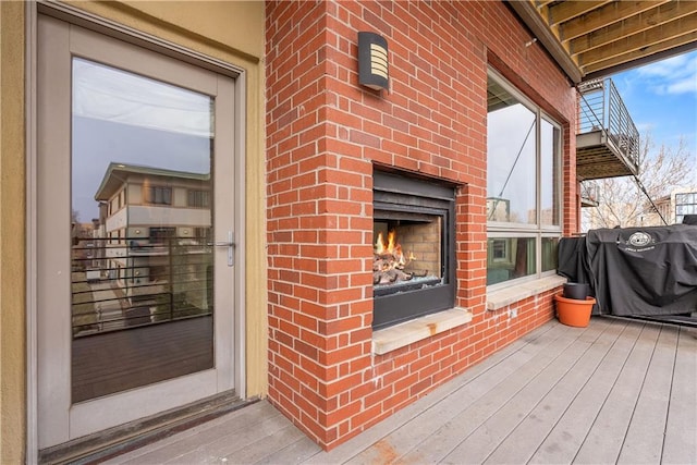 deck with a grill and an outdoor brick fireplace