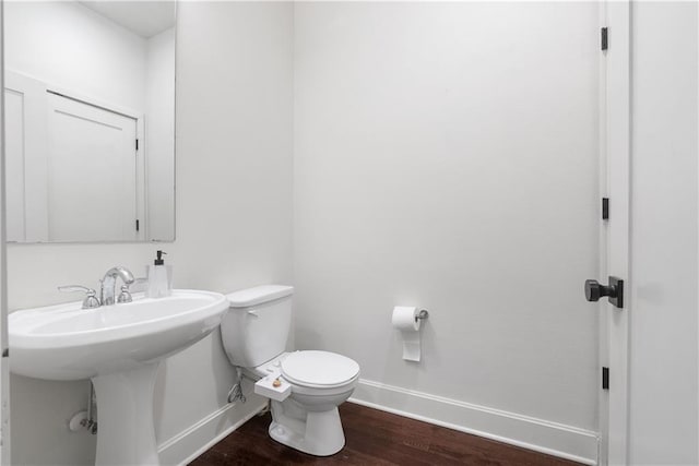 bathroom featuring a sink, baseboards, toilet, and wood finished floors