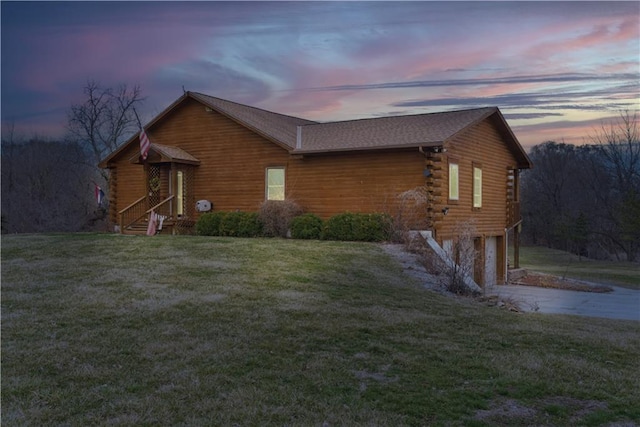 view of front of property with log siding, driveway, a lawn, and an attached garage