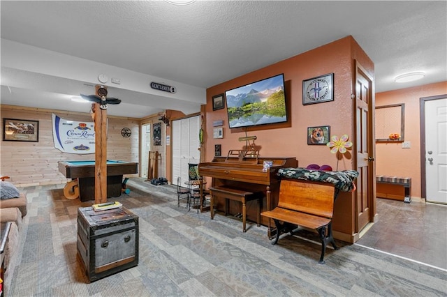 living area with wood walls, a textured ceiling, and billiards