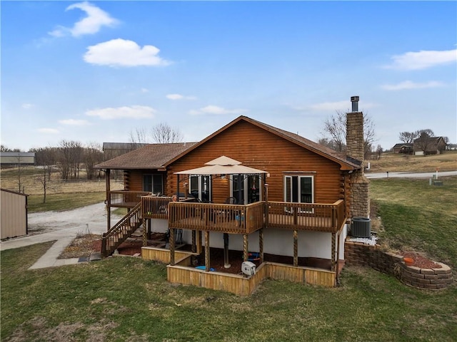 rear view of property featuring a lawn, driveway, a wooden deck, log exterior, and a chimney