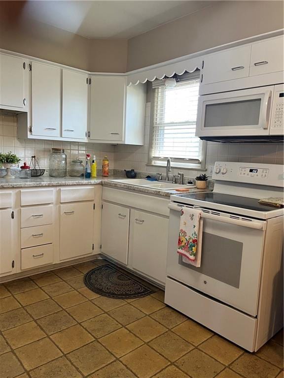 kitchen featuring white appliances, light countertops, tasteful backsplash, and a sink