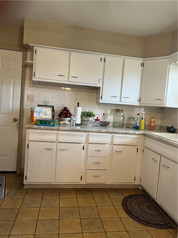 kitchen featuring decorative backsplash, light countertops, white cabinets, and a sink