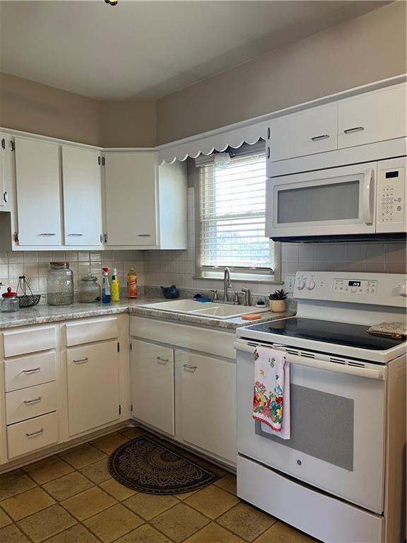 kitchen with decorative backsplash, white appliances, and a sink