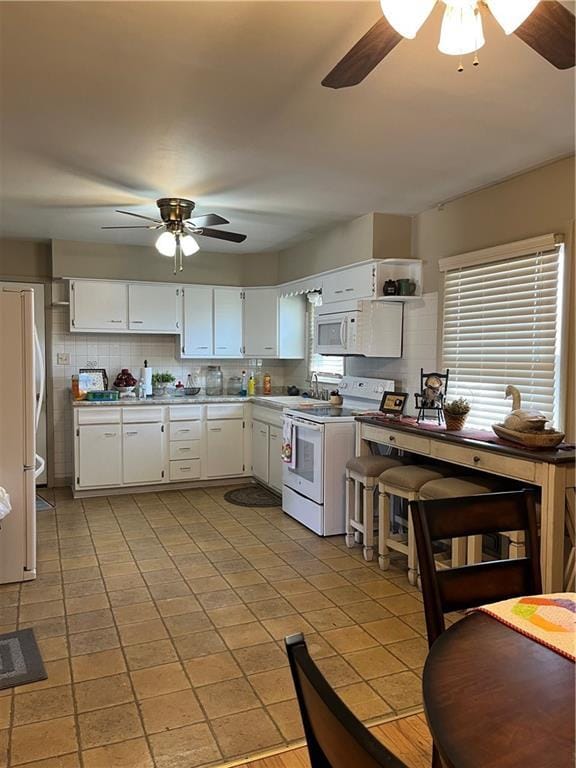 kitchen with white cabinetry, white appliances, a ceiling fan, and tasteful backsplash