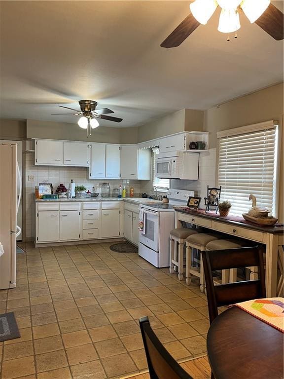 kitchen featuring white appliances, tasteful backsplash, ceiling fan, and white cabinetry