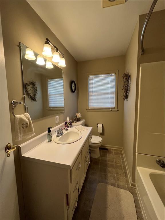 full bathroom featuring plenty of natural light, baseboards, toilet, and vanity