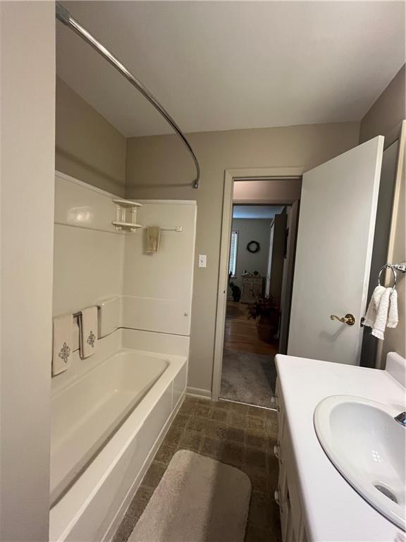 bathroom featuring baseboards, shower / tub combination, and vanity