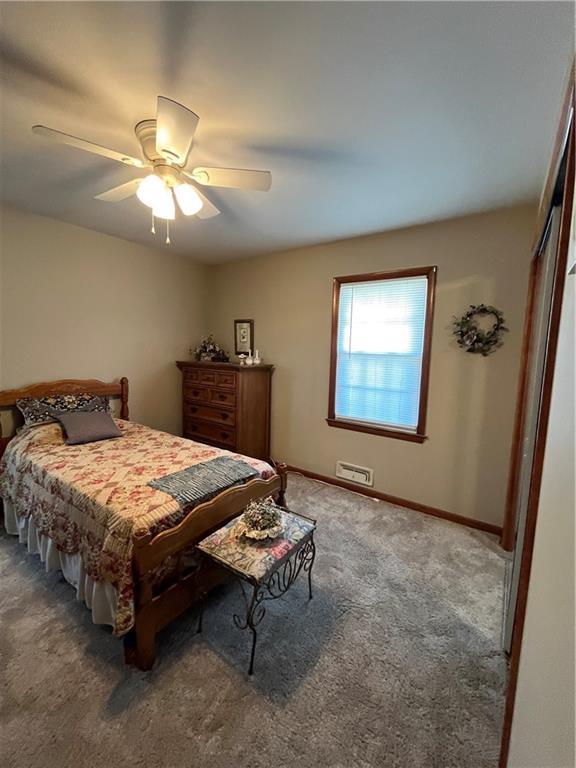 carpeted bedroom with visible vents, a ceiling fan, and baseboards