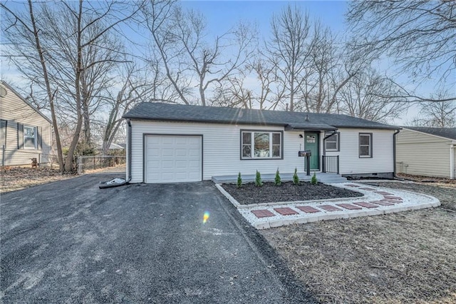 view of front facade featuring a garage, fence, and aphalt driveway