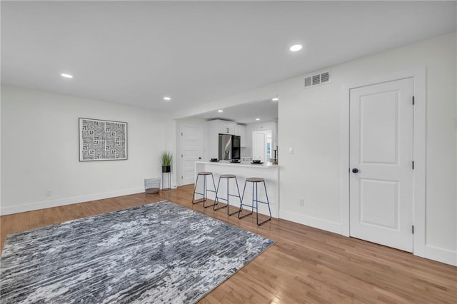 living area with light wood finished floors, visible vents, and recessed lighting