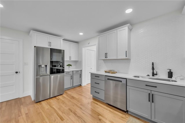 kitchen with a sink, stainless steel appliances, gray cabinetry, and light countertops