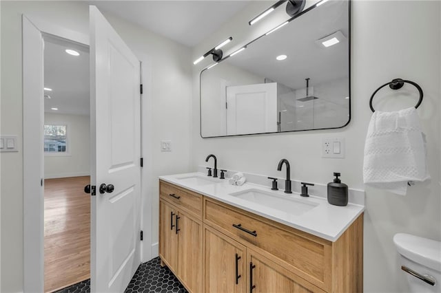 bathroom with double vanity, toilet, walk in shower, and a sink