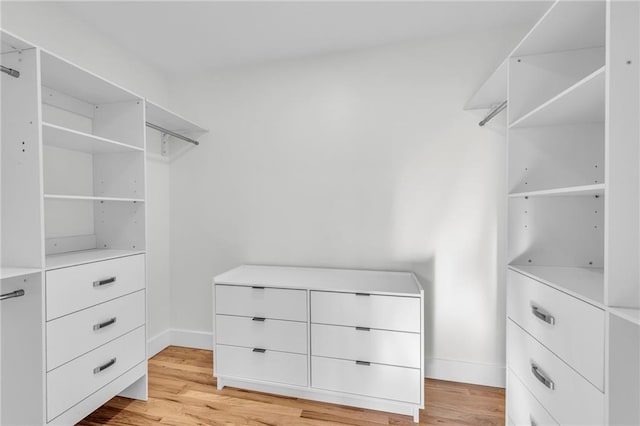 walk in closet with light wood-style floors