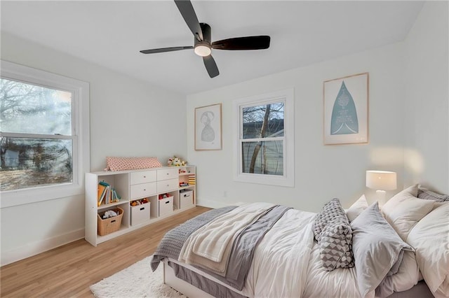 bedroom with a ceiling fan, light wood-style floors, and baseboards