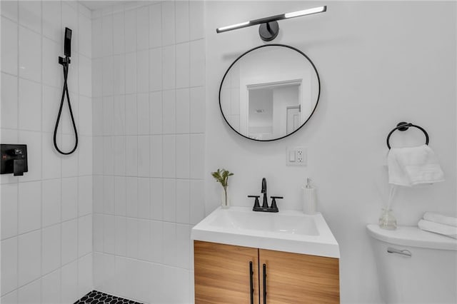 bathroom with tiled shower, toilet, and vanity