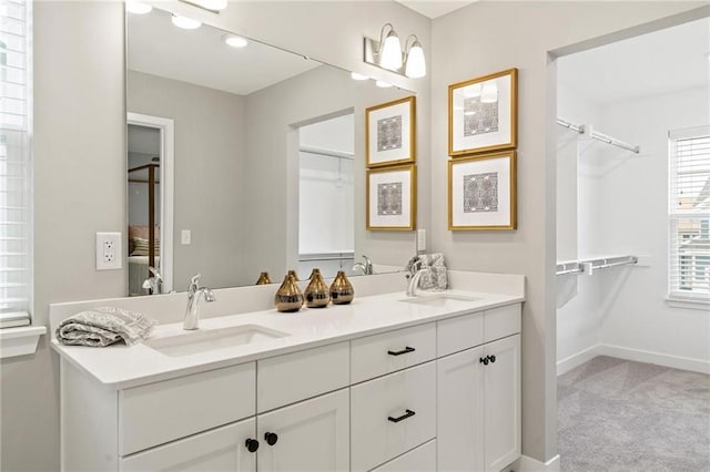 bathroom featuring double vanity, baseboards, and a sink