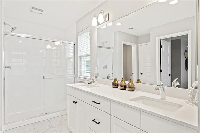 bathroom featuring a sink, marble finish floor, a stall shower, and double vanity