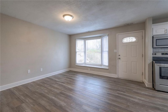 foyer entrance featuring visible vents, baseboards, a textured ceiling, and dark wood-style floors