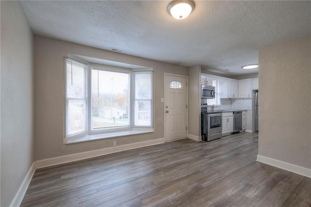 kitchen with tasteful backsplash, visible vents, dark wood-type flooring, appliances with stainless steel finishes, and white cabinets