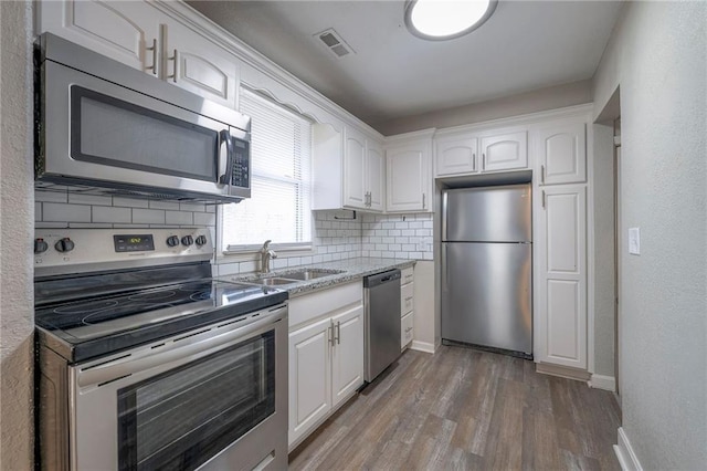 kitchen featuring white cabinetry, wood finished floors, appliances with stainless steel finishes, and a sink