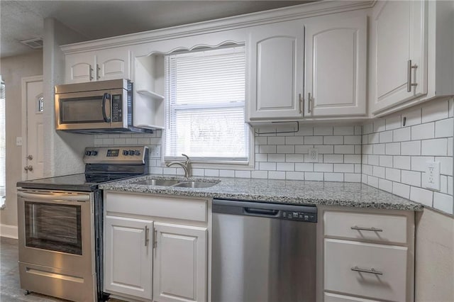 kitchen with visible vents, a sink, decorative backsplash, white cabinets, and appliances with stainless steel finishes