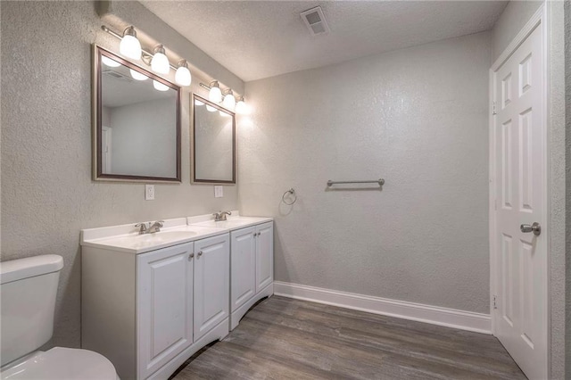 full bath featuring toilet, wood finished floors, baseboards, and a sink