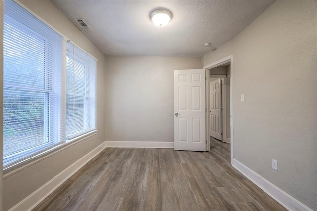 spare room featuring dark wood-style floors, visible vents, a textured ceiling, and baseboards